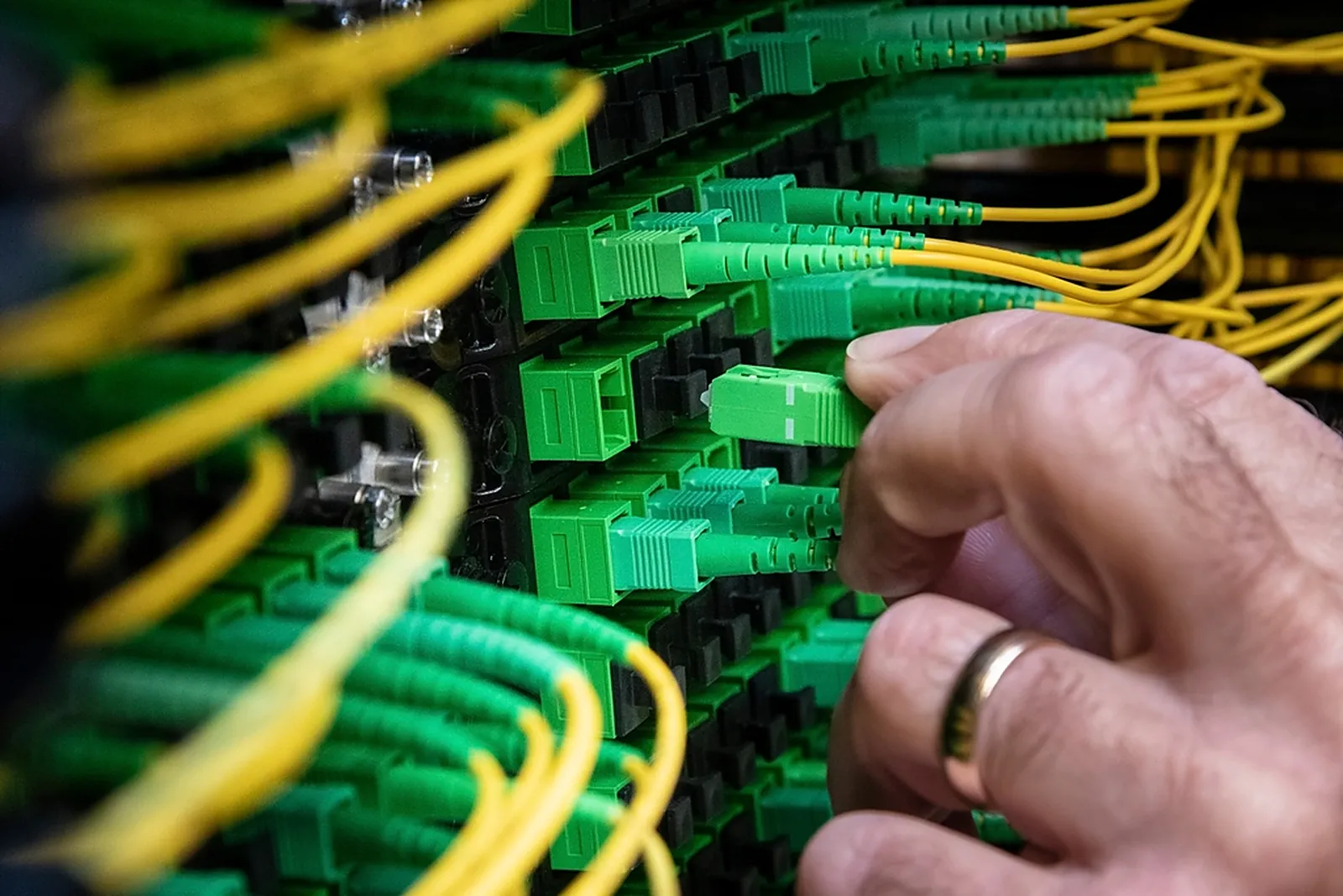 Hand steckt einen Lichtwellenleiter in ein Patchfeld